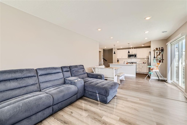 living area with light wood-type flooring, baseboards, and recessed lighting