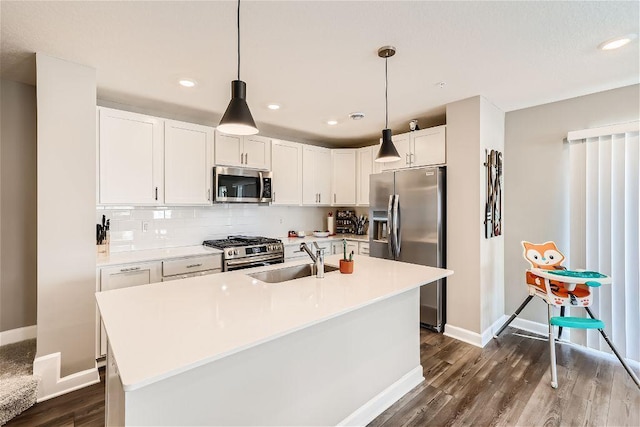 kitchen with appliances with stainless steel finishes, dark wood finished floors, a sink, and light countertops