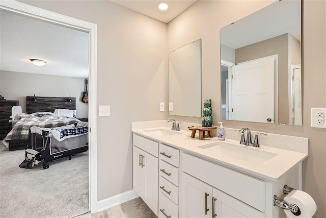 bathroom with connected bathroom, a sink, baseboards, and double vanity