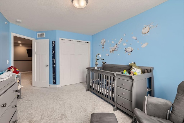 carpeted bedroom featuring a closet, visible vents, a textured ceiling, and baseboards