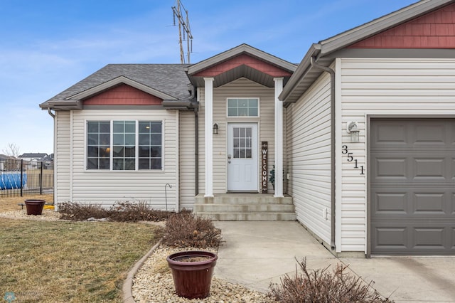 view of front of house with a shingled roof, fence, and a garage