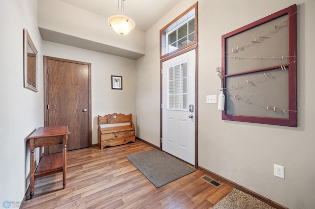 foyer entrance with light wood finished floors, visible vents, and baseboards