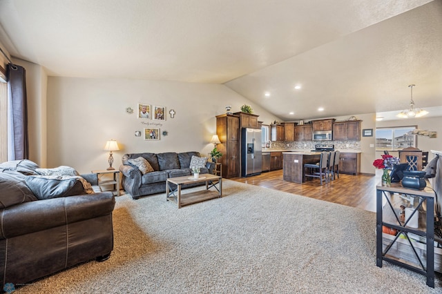 living room with vaulted ceiling, a chandelier, light wood-style flooring, and recessed lighting