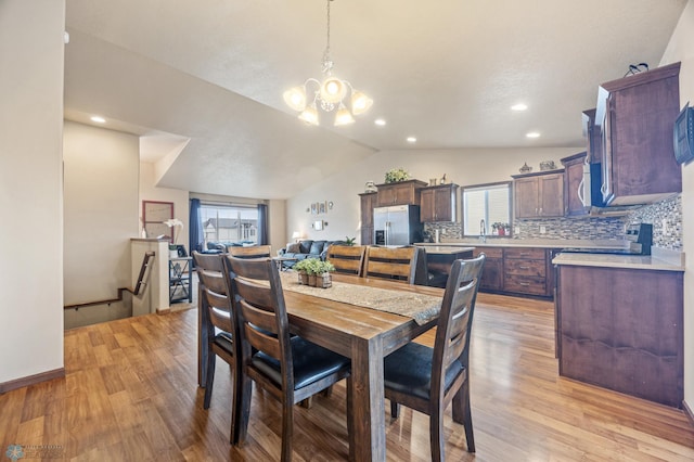 dining room with lofted ceiling, an inviting chandelier, light wood-type flooring, and recessed lighting