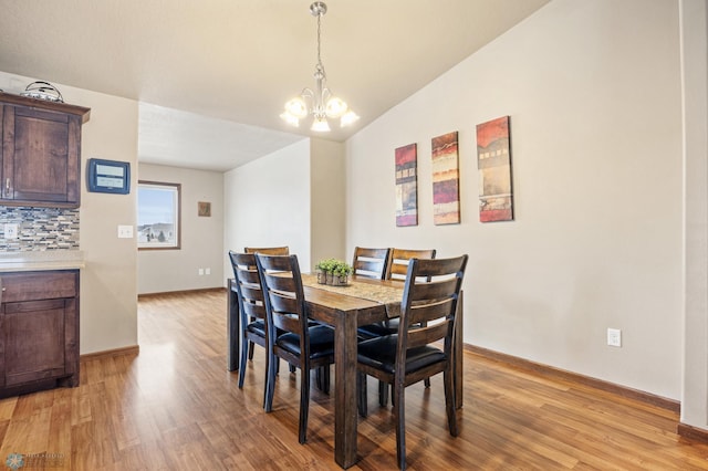 dining space featuring baseboards, light wood finished floors, and a notable chandelier