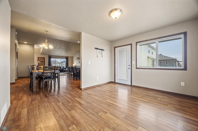 dining space featuring a textured ceiling, light wood finished floors, a chandelier, and a wealth of natural light