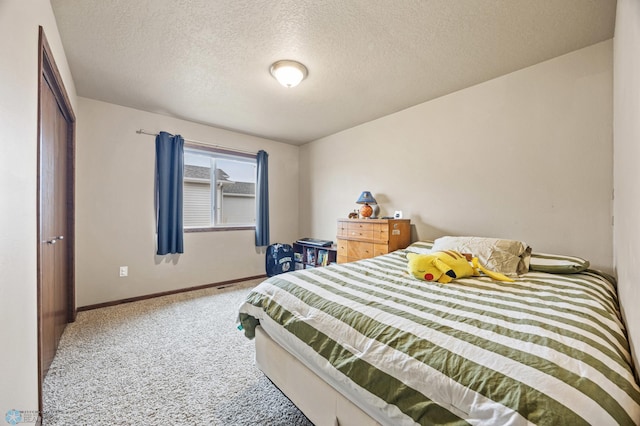 bedroom with a textured ceiling, baseboards, and carpet flooring