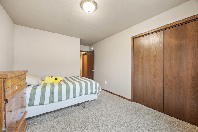 carpeted bedroom with a textured ceiling, a closet, and baseboards