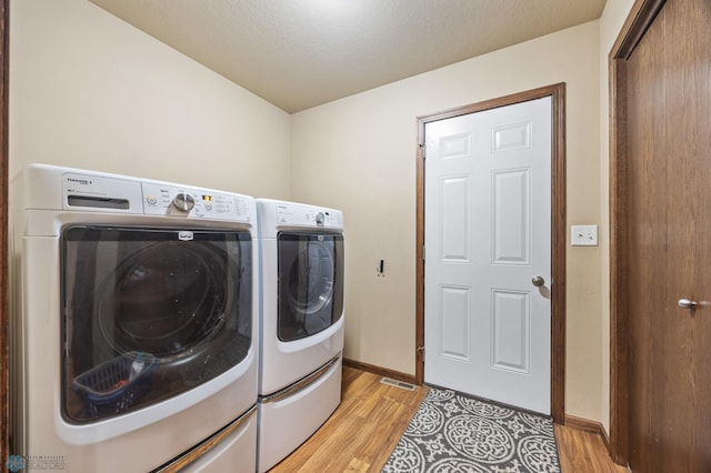 clothes washing area with laundry area, separate washer and dryer, light wood-type flooring, and baseboards