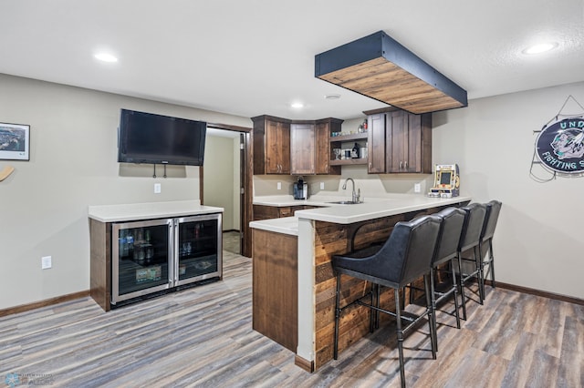 interior space featuring a breakfast bar, light wood finished floors, open shelves, a sink, and beverage cooler