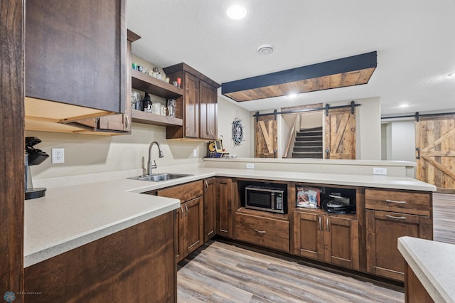 kitchen with a barn door, stainless steel microwave, light countertops, and a sink