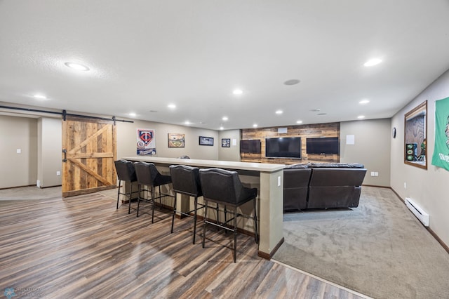 kitchen featuring a barn door, a baseboard radiator, a breakfast bar, and recessed lighting