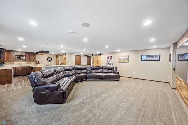 living room featuring a barn door, baseboards, light colored carpet, wet bar, and recessed lighting