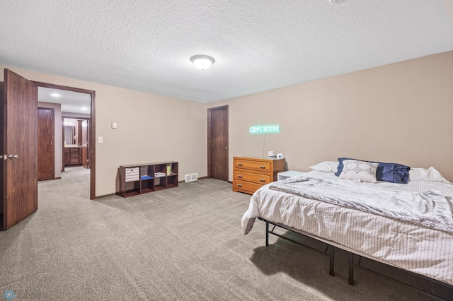 bedroom featuring a textured ceiling, light colored carpet, visible vents, baseboards, and a closet