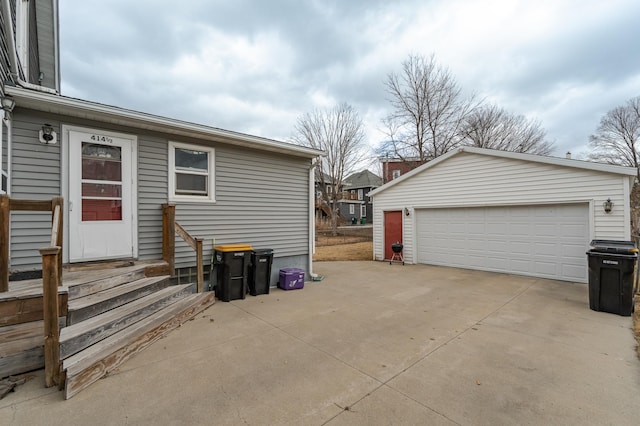 view of property exterior featuring entry steps, an outdoor structure, and a detached garage