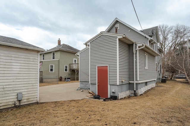 back of house with concrete driveway, a patio area, and a yard