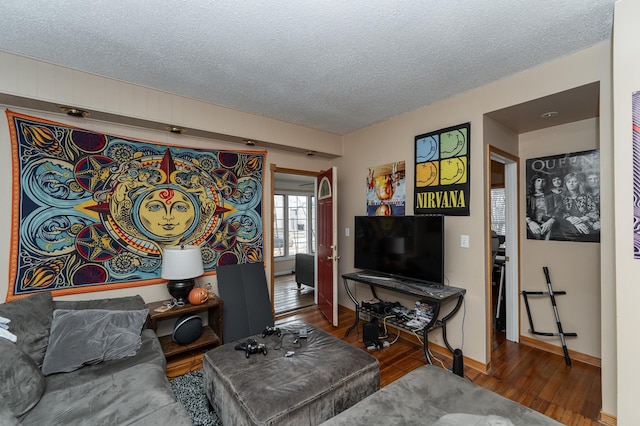 living area with a textured ceiling, baseboards, and wood finished floors