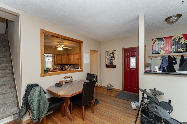 dining space featuring a textured ceiling, stairway, and wood finished floors