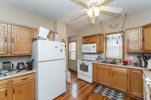 kitchen featuring a textured ceiling, white appliances, a sink, light countertops, and light wood finished floors