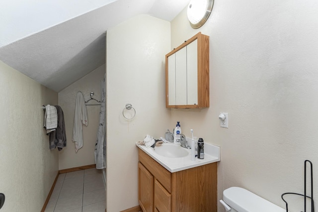 bathroom with tile patterned flooring, vaulted ceiling, vanity, and toilet