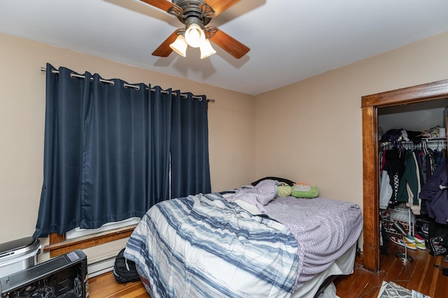 bedroom featuring a baseboard heating unit, a closet, wood finished floors, and a ceiling fan