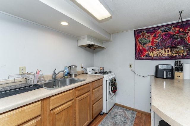 kitchen with light countertops, white gas range, and a sink