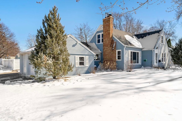 snow covered rear of property with a chimney and fence