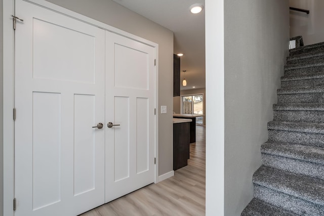 stairs featuring wood finished floors and recessed lighting