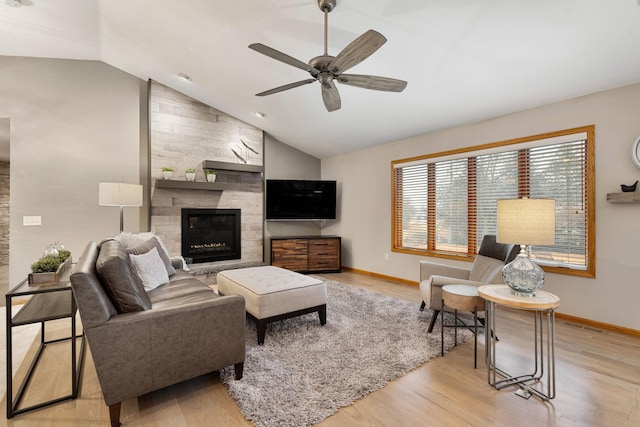 living room featuring a fireplace, light wood finished floors, vaulted ceiling, ceiling fan, and baseboards