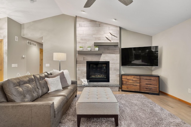 living room featuring a large fireplace, visible vents, lofted ceiling, ceiling fan, and wood finished floors