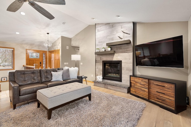 living area featuring recessed lighting, ceiling fan with notable chandelier, a fireplace, vaulted ceiling, and light wood-type flooring