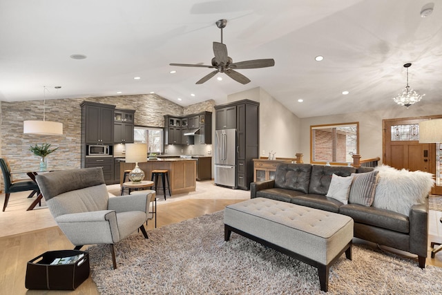 living room with vaulted ceiling, light wood finished floors, ceiling fan with notable chandelier, and recessed lighting