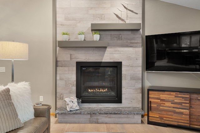 room details featuring a tiled fireplace and wood finished floors