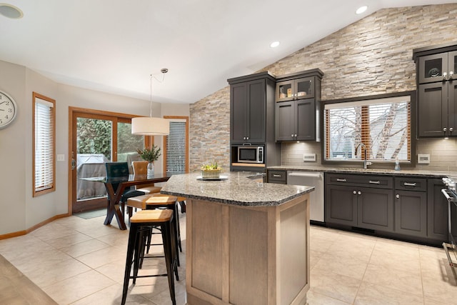 kitchen featuring vaulted ceiling, appliances with stainless steel finishes, backsplash, and a breakfast bar