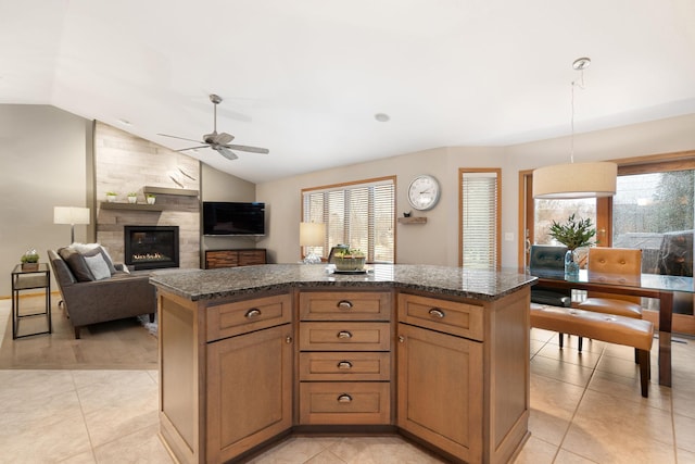 kitchen with vaulted ceiling, a tile fireplace, light tile patterned flooring, and a kitchen island