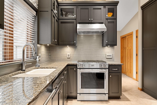 kitchen with a sink, light stone countertops, stainless steel appliances, backsplash, and exhaust hood