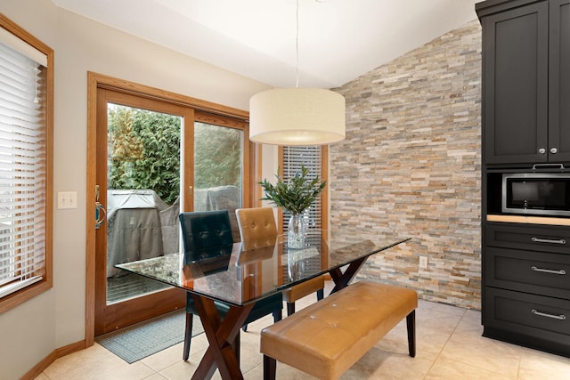 dining room with vaulted ceiling, baseboards, and light tile patterned floors