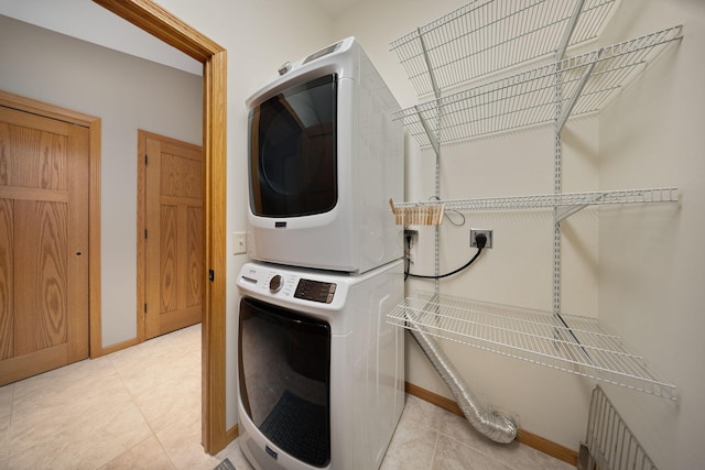 washroom featuring laundry area, light tile patterned floors, baseboards, and stacked washer and clothes dryer