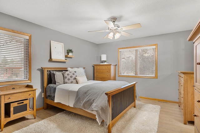 bedroom with light wood finished floors, baseboards, and a ceiling fan