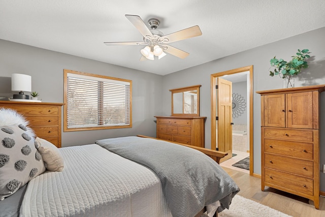 bedroom featuring light wood-style floors, ensuite bath, and a ceiling fan