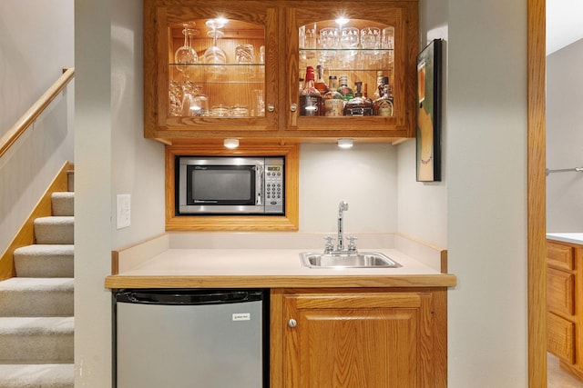 bar with appliances with stainless steel finishes, stairway, indoor wet bar, and a sink