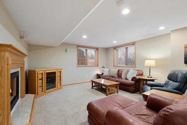 living area with baseboards, recessed lighting, a high end fireplace, and light colored carpet