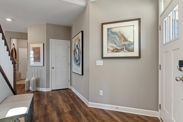 foyer entrance featuring stairs, dark wood-style flooring, and baseboards