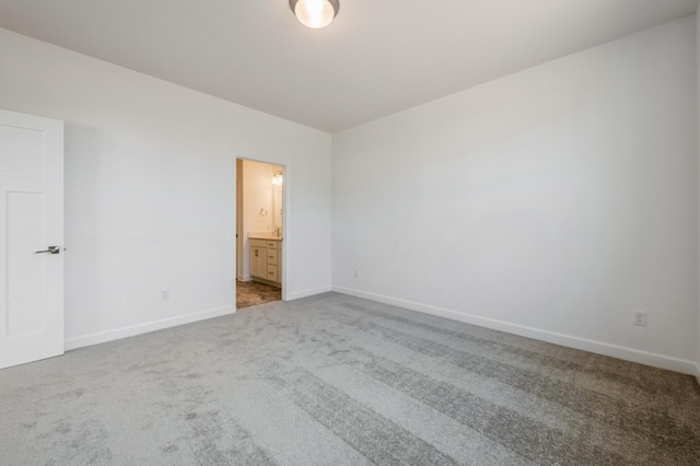 unfurnished bedroom with carpet flooring, baseboards, and ensuite bathroom