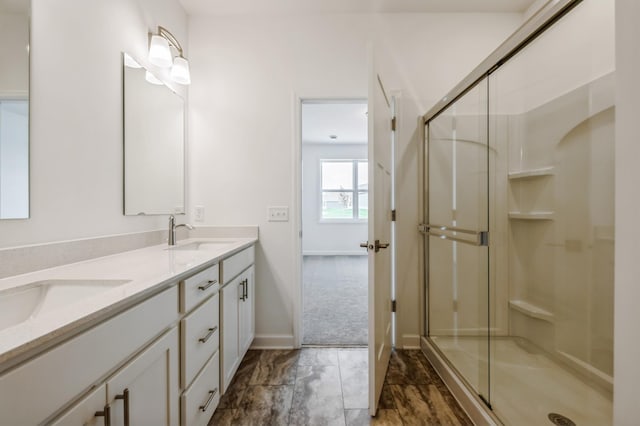 full bath with marble finish floor, double vanity, a sink, a shower stall, and baseboards