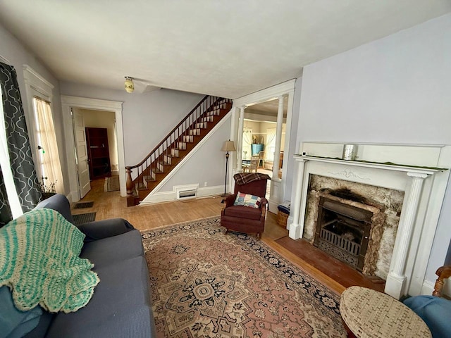 living room featuring stairway, a premium fireplace, wood finished floors, and baseboards