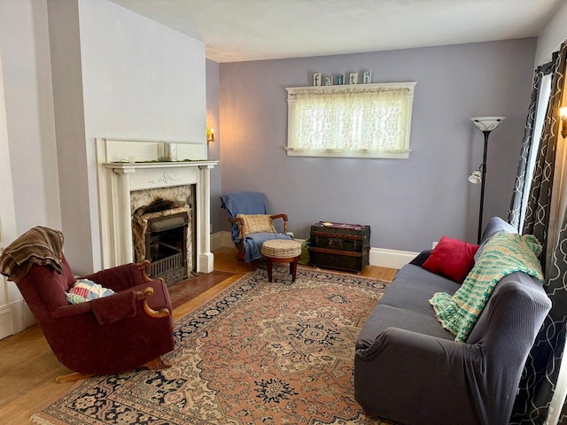 living area with baseboards, a fireplace with flush hearth, and wood finished floors