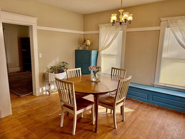 dining area with light wood-style floors and a notable chandelier