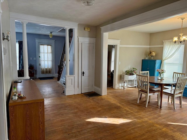 dining room with stairs, decorative columns, a notable chandelier, and wood finished floors