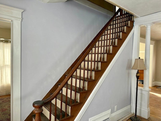 staircase with visible vents, baseboards, wood finished floors, and decorative columns